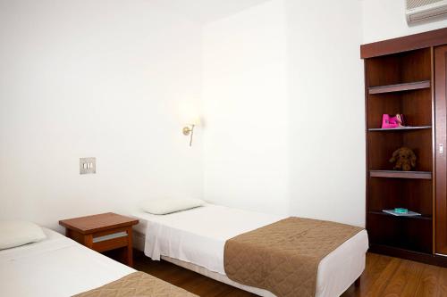 a bedroom with two beds and a book shelf at Cyprotel Faliraki in Faliraki