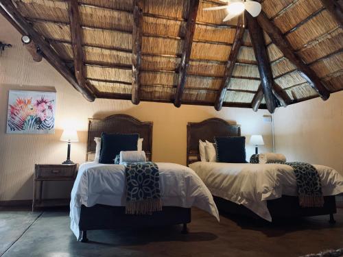 Duas camas num quarto com tectos em madeira em Makhato Bush Lodge 111 em Bela-Bela