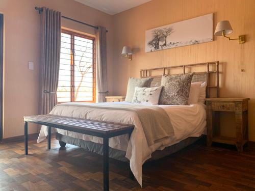 a bedroom with a bed with a bench and a window at Makhato Bush Lodge 111 in Bela-Bela