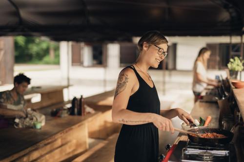 a woman cooking in a pan in a kitchen at Forest Camping Mozirje in Mozirje