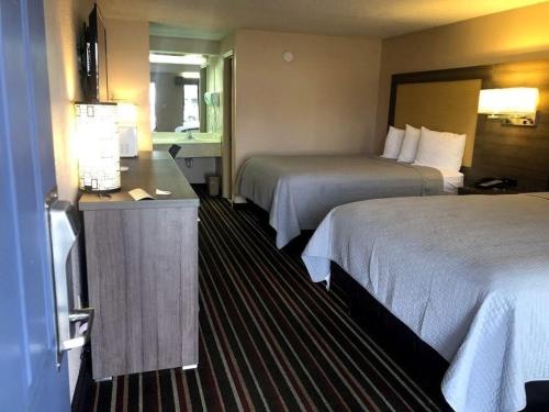 a hotel room with two beds and a desk at Legacy Inn - Gallatin in Gallatin