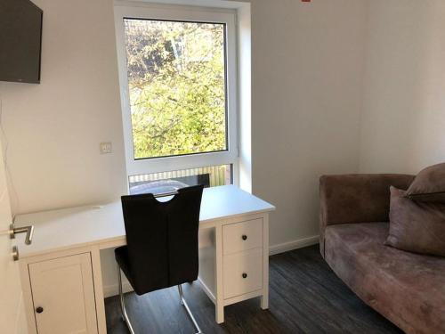 escritorio con silla y ventana en una habitación en Apartment Strandperle, en Aurich