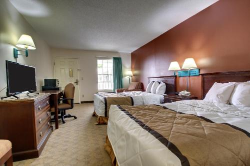 a hotel room with two beds and a desk at Key West Inn - LaFayette in LaFayette