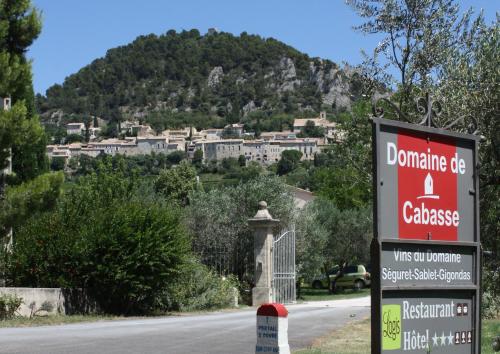 a sign for a house on a road with a mountain at Hotellerie du Domaine de Cabasse in Séguret