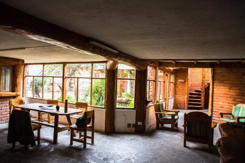 a room with a table and chairs and windows at Jardín de Rosas Hostel in El Bolsón