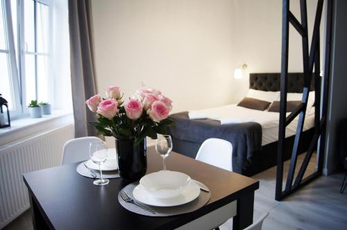 a table with a vase of pink roses on it at Black & White Apartament in Toruń