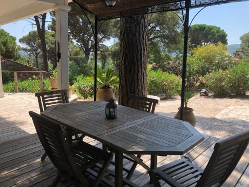 uma mesa de madeira e cadeiras num alpendre em Saint tropez -parc oasis em Gassin