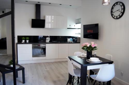 a kitchen with a black table and white cabinets at Black & White Apartament in Toruń