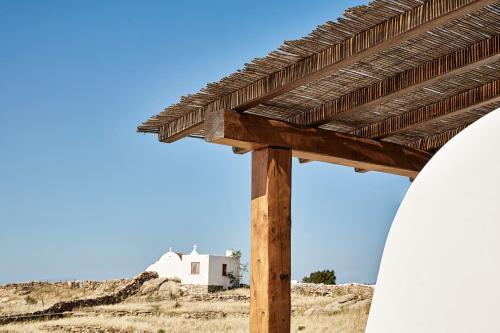 a wooden pergola with a building in the background at Almyra Guest Houses in Paraga