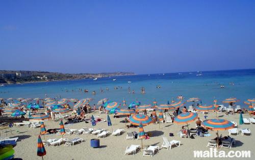a group of people on a beach with umbrellas at Francis Flats Modern Penthouse in Mellieħa