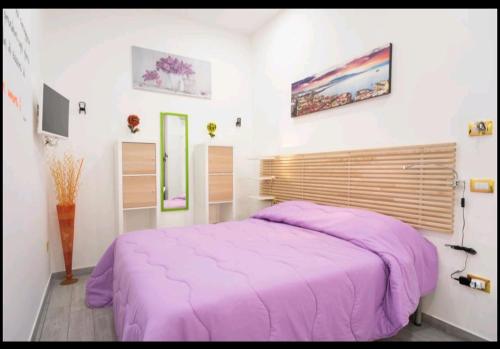 um quarto com uma cama com um cobertor roxo em Flower Power em Nápoles