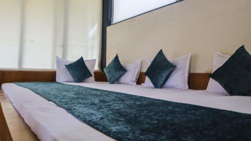 ein großes Bett mit weißen Kissen und einem großen Fenster in der Unterkunft Jungle Safari Resort & Holiday Villa in Nashik