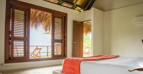 a bedroom with a bed and a window with a view at Villa Playa Tayrona, Los Naranjos in Los Naranjos