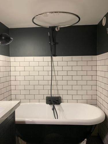 une baignoire blanche avec une lumière au-dessus dans l'établissement Les Apparts de Charly Duplex cosy au marché hyper centre La Rochelle tout à pied, à La Rochelle