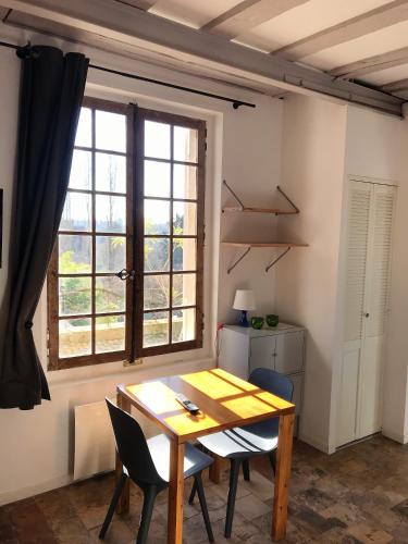 une table et des chaises dans une pièce avec une fenêtre dans l'établissement Appartement spacieux avec une vue sur Tours ( 38m²) -Gite de Bellevue, à Tours