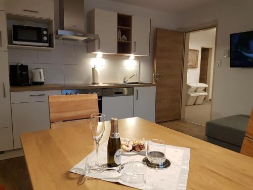 a table with a bottle of wine and two glasses at Haus Alpenglühn in Sautens