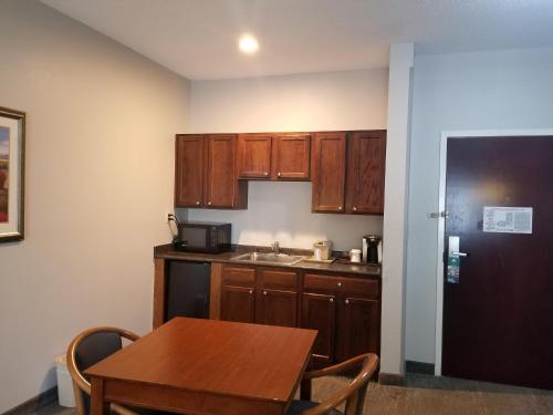 a small kitchen with wooden cabinets and a table at Wingate by Wyndham Savannah I-95 North in Port Wentworth