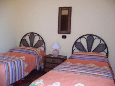 a bedroom with two beds and a table with a lamp at Villa Laura in Coccorino