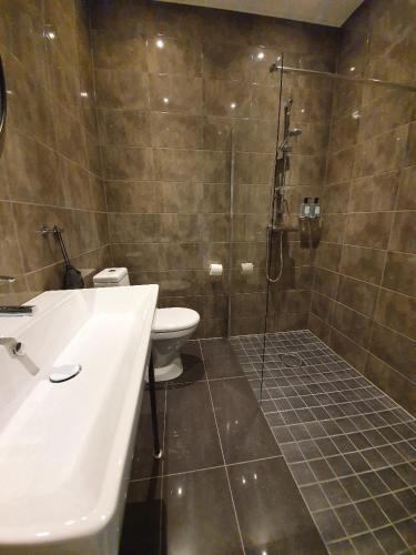 a bathroom with a shower and a toilet and a sink at Hotell Carl Friman in Motala