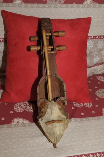 a wooden violin sitting on a bed next to a red pillow at La Maison Everest 73 - bilocale a La Ruine, Morgex in Morgex