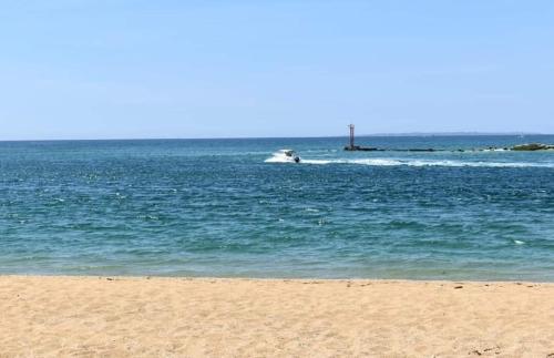a beach with a boat in the water at Abri du pêcheur in Étel