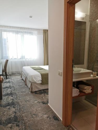 a bedroom with a bed and a bathroom with a sink at YMY Boutique Residence in Bucharest