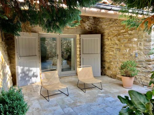 two chairs sitting on a patio in front of a building at La Maison des Vendangeurs - TABLE D'HÔTES le soir du jeudi au dimanche- Jacuzzi - Balnéo SPA - ACCES PISCINE pour toutes les chambres sauf STUDIO COQUET- Piscine de mai à mi-octobre in Martignargues