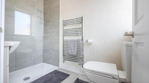 a white bathroom with a toilet and a shower at The Abbey Apartment in Hexham