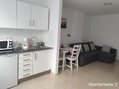 eine Küche und ein Wohnzimmer mit einem Sofa und einem Tisch in der Unterkunft Apartamento Kings Vegueta in Las Palmas de Gran Canaria