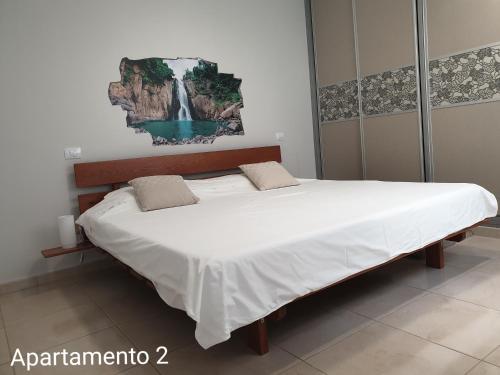 a large bed in a bedroom with a waterfall painting on the wall at Apartamento Kings Vegueta in Las Palmas de Gran Canaria