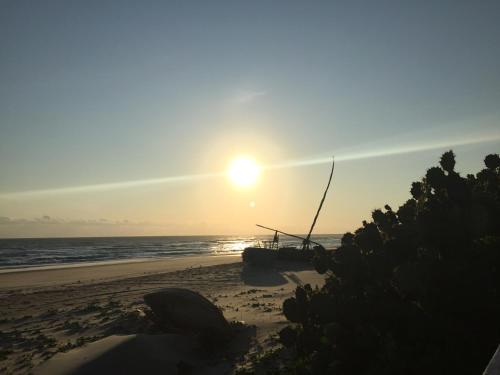 a sunset on the beach with a boat on the beach at Pousada Vila Mar in Beberibe