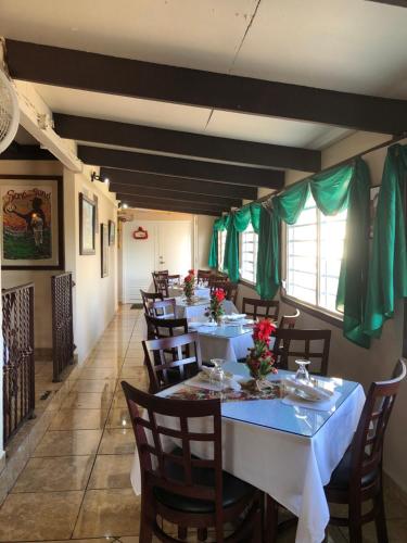 ein Esszimmer mit Tischen, Stühlen und grünen Vorhängen in der Unterkunft Tio Pepe’s Guest House in Aibonito