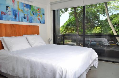 1 dormitorio con cama blanca y ventana grande en 中国人之家公寓酒店Apart-Hotel Casa de China en Managua