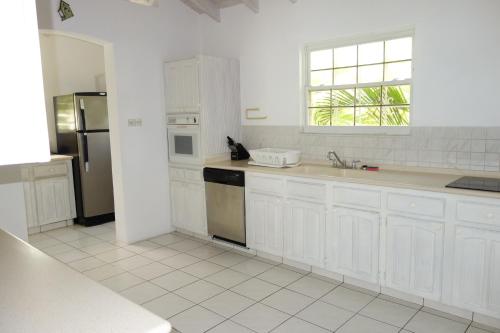 a white kitchen with white cabinets and a window at Inchcape Seaside Villas in Christ Church
