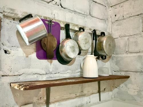 a shelf with pots and pans hanging on a brick wall at Quitinetes Rusticas Junto a Natureza - Bruxas e Bruxos in Porto Seguro