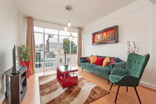 a living room with a green couch and a window at Roma Sur Apartments with Balcony - Family Friendly in Mexico City
