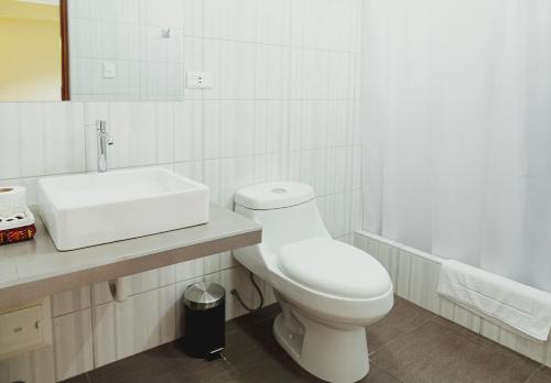 a white bathroom with a toilet and a sink at Mauri in Huánuco