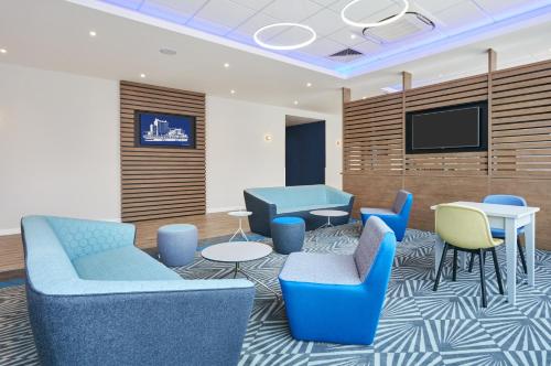 uma sala de espera com cadeiras azuis e uma televisão de ecrã plano em Holiday Inn Express Grimsby, an IHG Hotel em Grimsby
