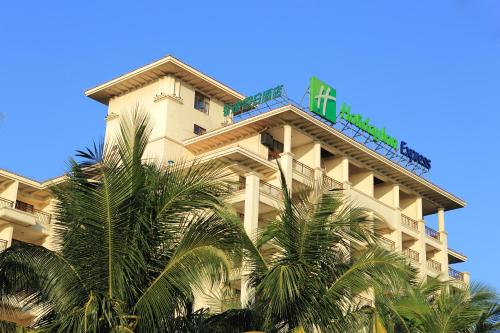 a tall building with palm trees in front of it at Holiday Inn Express Haikou West Coast by IHG in Haikou