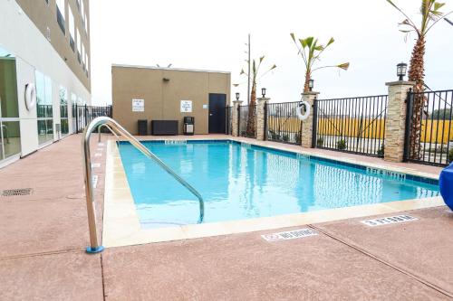 a swimming pool with a hand rail next to a building at Holiday Inn Express & Suites - Houston IAH - Beltway 8 by IHG in Houston