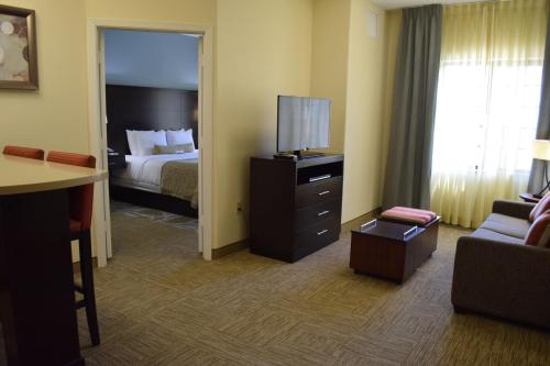 a hotel room with a bed and a television at Staybridge Suites Houston Stafford - Sugar Land by IHG in Stafford