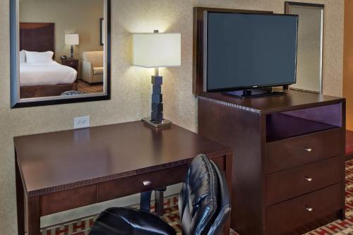 a room with a desk with a television and a bed at Holiday Inn Jacksonville E 295 Baymeadows by IHG in Jacksonville