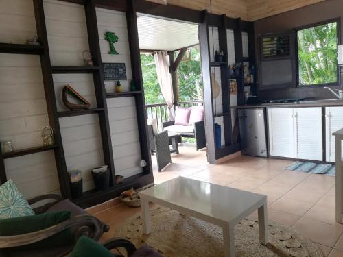 a living room with a table and a kitchen at Vanille Lodge in Le Marin