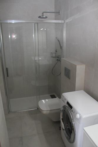 uma casa de banho com um chuveiro e uma máquina de lavar roupa em Apartamento Iceberg Tarifa Parking gratuito em Tarifa