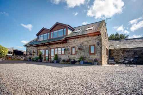 a stone house on a gravel driveway at Roman Height's Holiday Cottages in Haltwhistle
