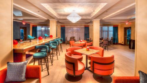 a restaurant with orange chairs and tables and a bar at Holiday Inn Express Wichita South by IHG in Wichita