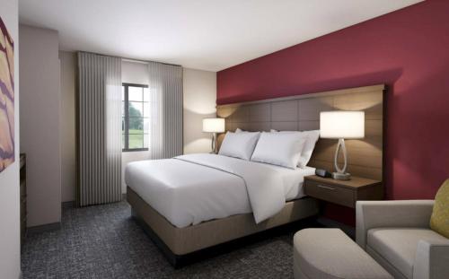 ein Schlafzimmer mit einem großen weißen Bett und einem Stuhl in der Unterkunft Staybridge Suites - Lafayette, an IHG Hotel in Lafayette