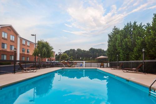 einem Pool mit blauem Wasser vor einem Gebäude in der Unterkunft Holiday Inn Express Winston-Salem, an IHG Hotel in Winston-Salem