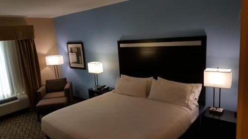 a hotel room with a bed and a chair and two lamps at Holiday Inn Express and Suites Atascocita - Humble - Kingwood by IHG in Humble
