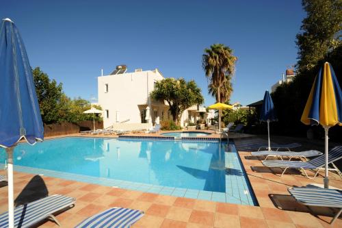 a swimming pool with chairs and umbrellas at Evilion hotel in Stalos